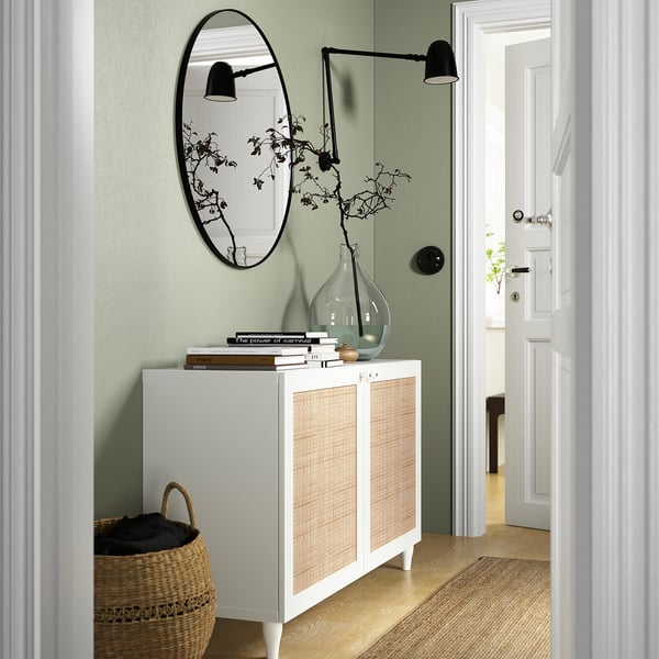 White BESTÅ sideboard with woven doors, mirror, and decor in green entry.