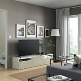 Gray living room with BESTÅ tv bench, flat-screen tv, art, dark wood floors, glass coffee table.