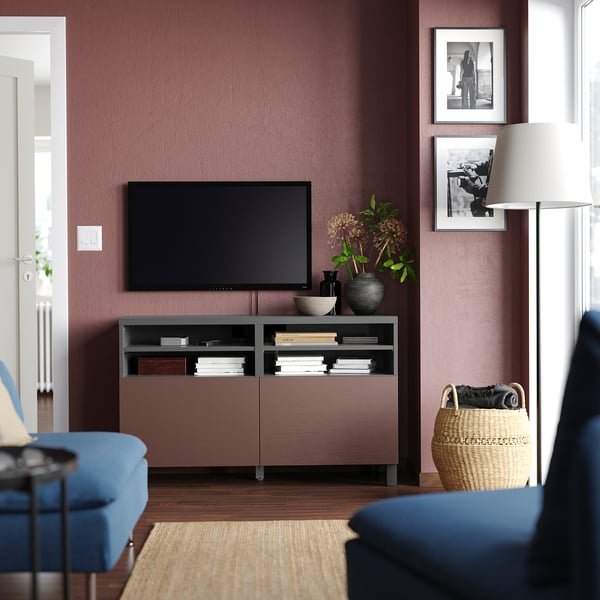 Modern living room with a BESTÅ tv bench in brown. A tv, blue sofa, and decorative items.