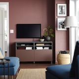 Modern living room with a BESTÅ tv bench in brown. A tv, blue sofa, and decorative items.