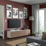 Modern living room with burgundy walls, featuring a BESTÅ tv bench, flat screen, books, vase, photos, lamp, window, and cozy setup.