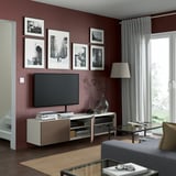 Modern living room with red walls, BESTÅ tv bench, photos, and lamp.