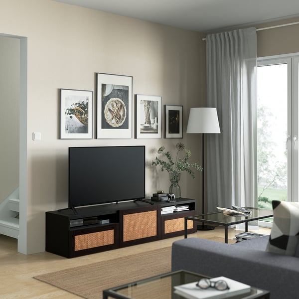 Modern living room with BESTÅ tv bench, pictures, grey curtains, glass table. Tv centered, lamp, vase on right. Bright light.