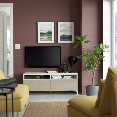 Modern living room with purple walls, a flat screen tv on a cream BESTÅ tv stand, yellow seating, and green plants.