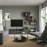 Modern living room with BESTÅ tv bench, sofa, coffee table, & record player. Gray walls, shelves, large window.
