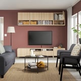 Modern living room with maroon walls, gray sofa, armchair, and BESTÅ tv storage.