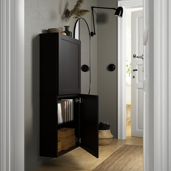 Black wall-mounted cabinet with open doors revealing books, baskets, and adjustable shelves. Soft-close hinges.