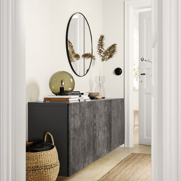 Modern entryway with BESTÅ gray storage unit, round mirror, lamp, flowers, basket, and white doors.
