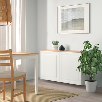 White BESTÅ sideboard with adjustable shelves, between table and plant, adds clean, organized feel to minimalist decor.