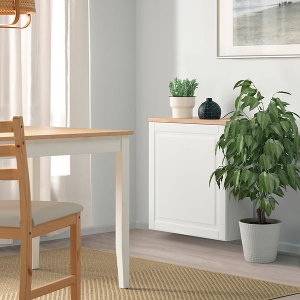 Minimalist dining area with BESTÅ sideboard, plant, and matching table/chairs, soft light from window.