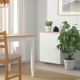 Minimalist dining area with BESTÅ sideboard, plant, and matching table/chairs, soft light from window.