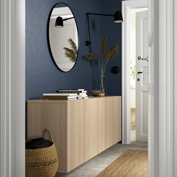 Minimalist entryway: BESTÅ sideboard, mirror, sconces, books, vase, basket.