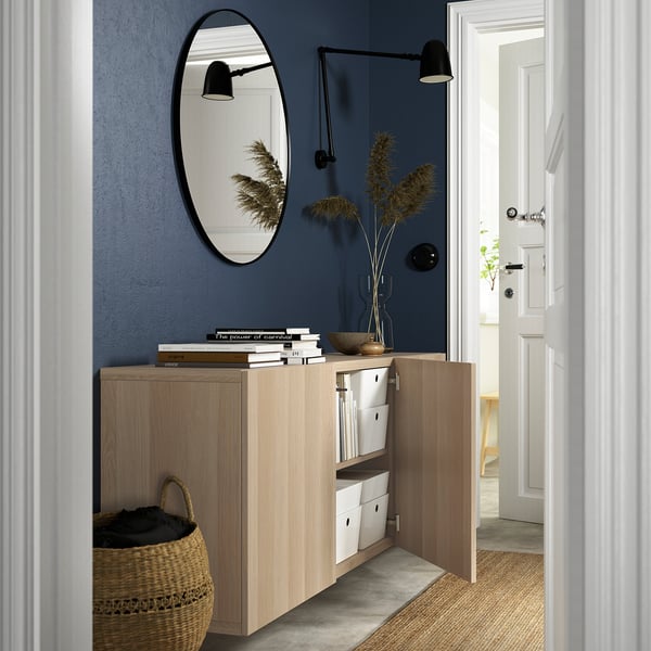 Modern, wall-mounted wooden cabinet with open doors revealing storage boxes, showcasing an airy and organized look.
