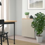 Minimalist room with BESTÅ off-white cabinet & black table, chair, and floor plant.