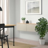 Modern living room with BESTÅ storage, plants, chair, desk, nature print.
