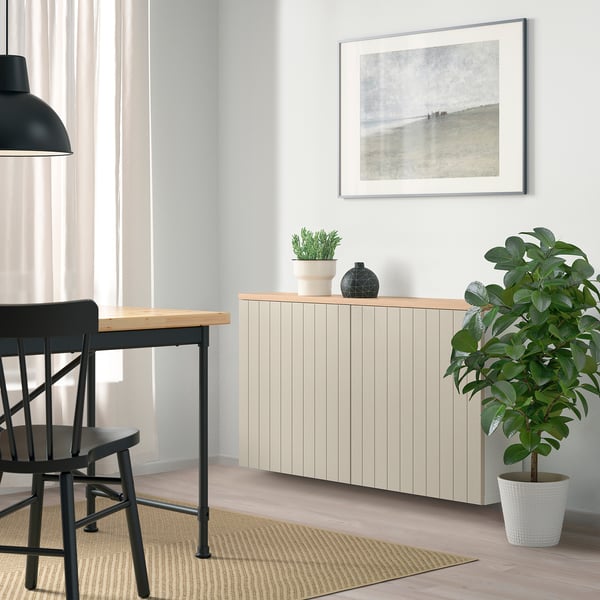 Minimalist room with BESTÅ sideboard, plants, art, & simple chair. Light floor & beige rug.