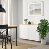 Modern dining space with BESTÅ sideboard, table, and chair. Decor includes black vase, plant, and framed picture.