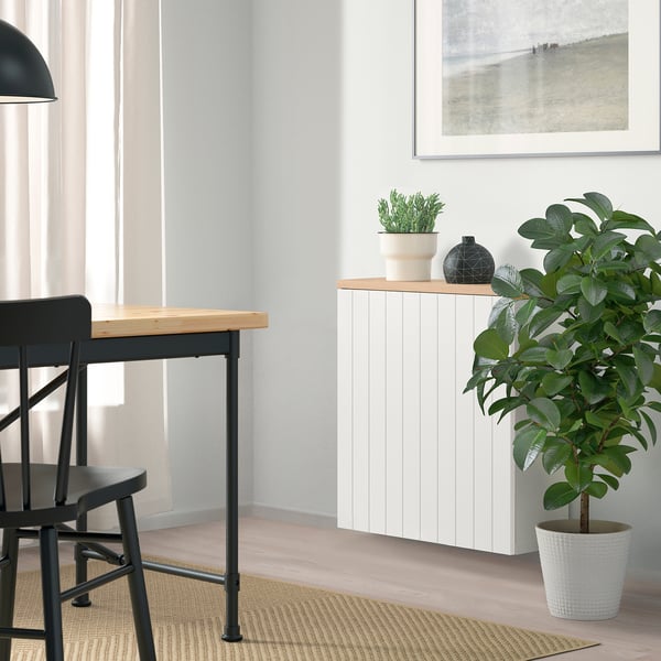 Minimalist dining area with wooden table, black chairs, BESTÅ storage, plants, and window.