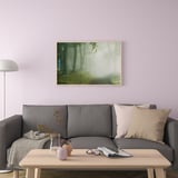 Modern living room with grey couch, wooden table, and misty forest wall art.