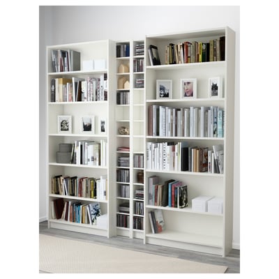 White BILLY bookcases with adjustable shelves, filled with books, cds, and photo frames, anchored to the wall.