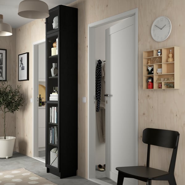 Cozy hall with tall BILLY bookcase, white door, black chair, plant.