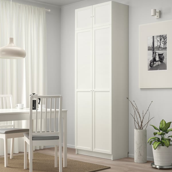 Minimalist dining space with tall BILLY bookcase, green plant.