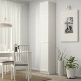 Minimalist dining area with white BILLY bookcase, potted plant, framed scooter photo, and white chairs around a table.
