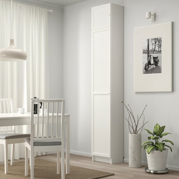 Modern dining area with BILLY bookcase, chairs, table, photo, and plant.