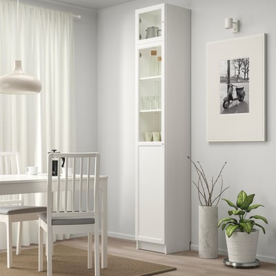 Modern dining area with BILLY bookcase, glass panels, and plant.