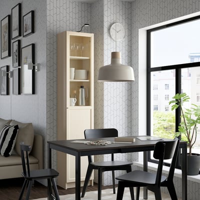 Modern dining area with black table, chairs, a tall light-colored BILLY bookcase with a glass door, and a large window.