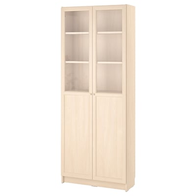 Light wooden BILLY bookcase with glass doors and stores items.