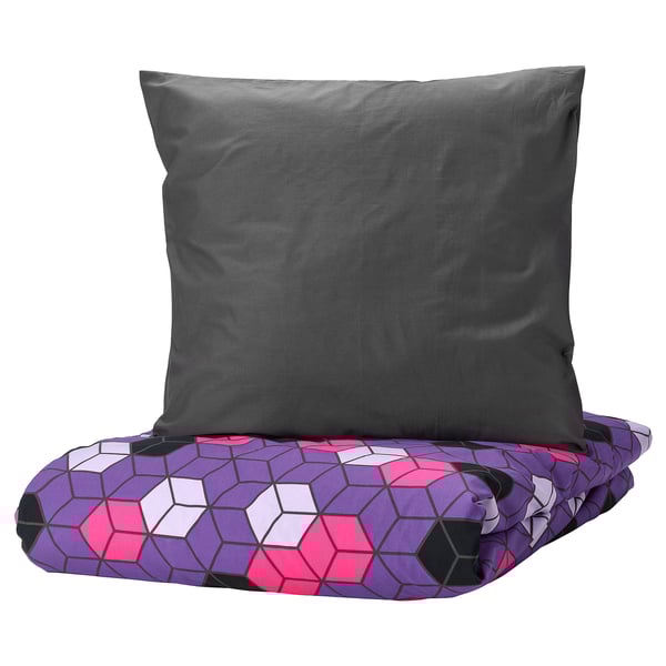 Gray pillow on colorful geometric purple bed cover.