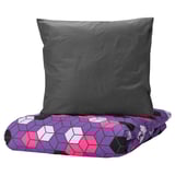 Gray pillow on colorful geometric purple bed cover.