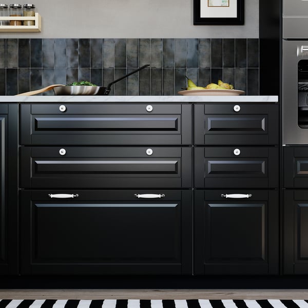 Modern kitchen with BODBYN black cabinets, marble countertop, green vegetables, and stainless steel appliances.
