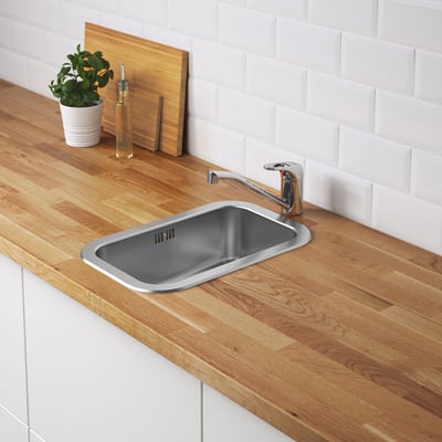 Small, stainless steel kitchen sink embedded in wooden countertop with silver tap.