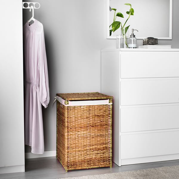 A natural woven rattan laundry basket, labeled BRANÄS, sits beside a white chest of drawers, appearing smaller in comparison.