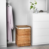 A natural woven rattan laundry basket, labeled BRANÄS, sits beside a white chest of drawers, appearing smaller in comparison.