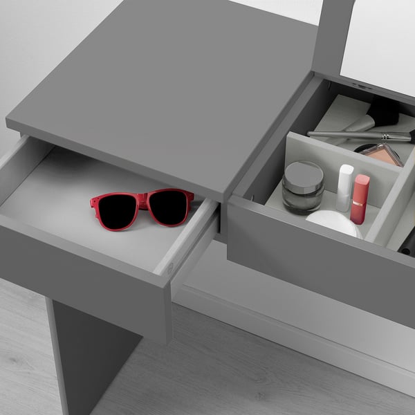 Open desk with red sunglasses left drawer, make-up right drawer, gray top.