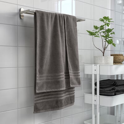 A BROKGLIM gray towel on a metal rod, large, soft, absorbent, organic cotton with woven border in bathroom.