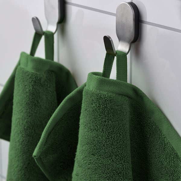 Green organic towels hang on stainless hooks.