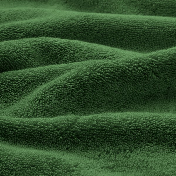 Folded green towels, soft and plush, made of organic cotton, neatly stacked, showing quality texture.