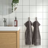 Gray towels on hooks in modern bathroom. Gots-certified, thick, absorbent, decorative border, oversized.
