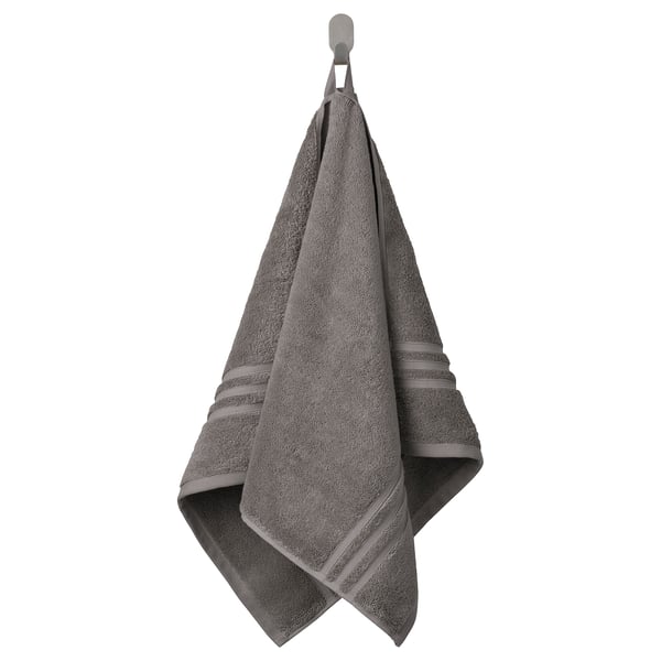 A gray BROKGLIM towel hangs neatly on a hook, showcasing an elegant woven border. Made of organic cotton, it offers a soft, absorbent texture.