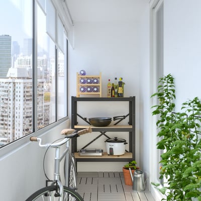Kitchen balcony with BROR shelf, cookware, bike, plant, city view.