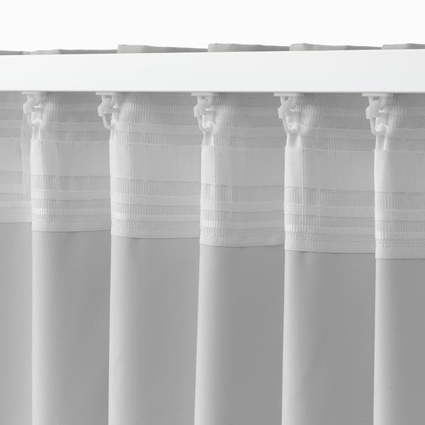White room-darkening curtains hanging vertically, adjustable via hooks, blocking light.