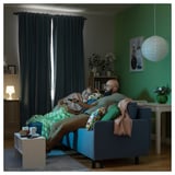 Cozy living room: dad and daughter relax on blue BRUKSVARA curtains, with green walls, wooden floor, and hanging lamp.
