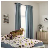 Cozy bedroom with polka dot bedding, blue curtains, dog cuddling sleeper, colorful decor, wooden cabinet, wall art.