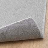 Light grey, soft, durable rug on wooden floor. Stain-resistant & cozy, perfect for living or bedroom. Anti-slip underlay needed.