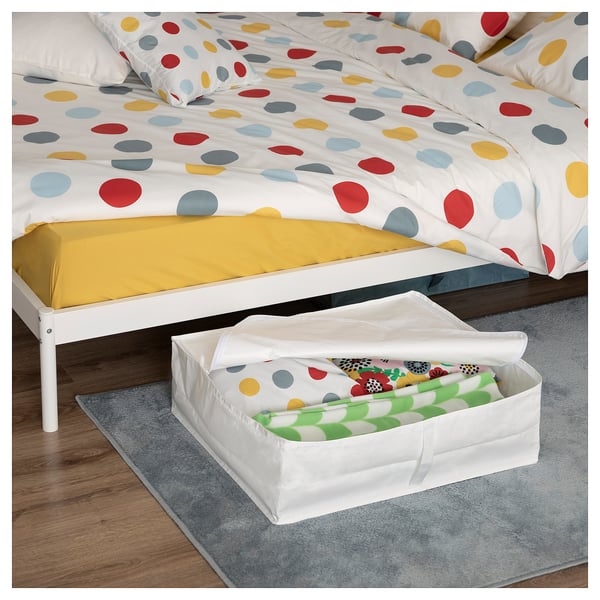 Bedroom scene with polka dot bedding and white storage box under the bed.