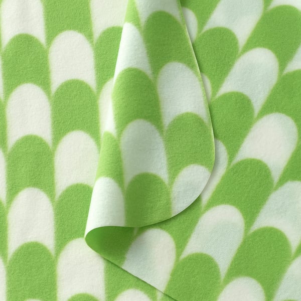 Soft, folded green and white patterned throw blanket; inviting and cozy.